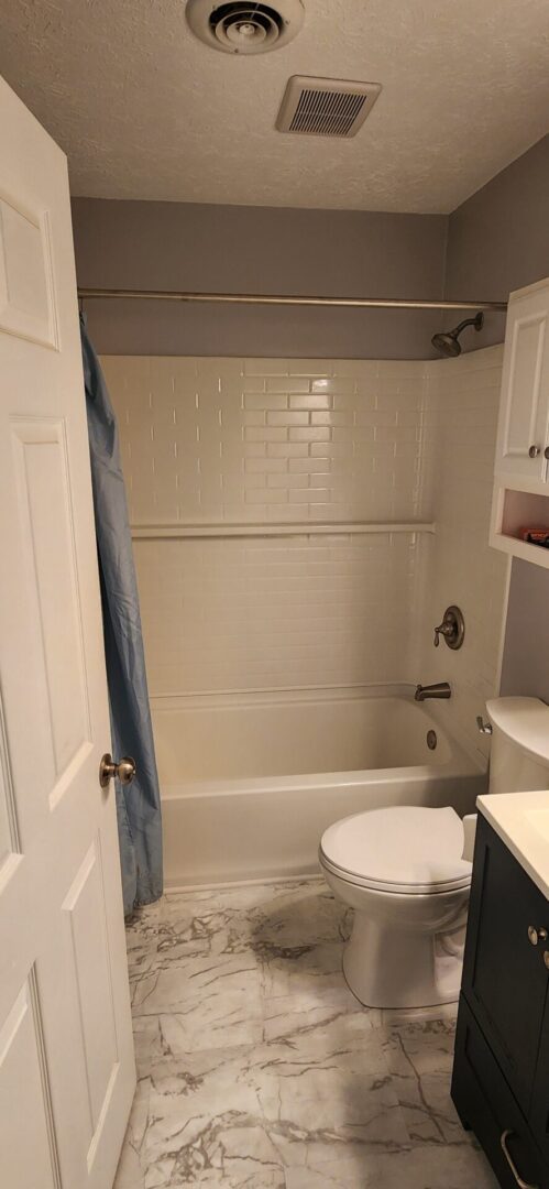 A bathroom with white tile and a toilet.