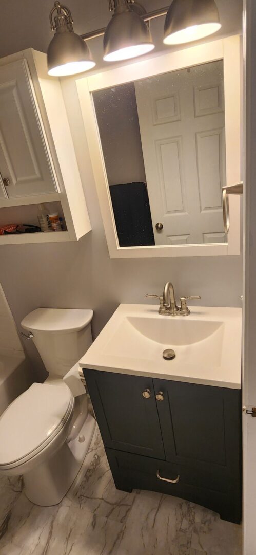 A bathroom with a toilet, sink and mirror.