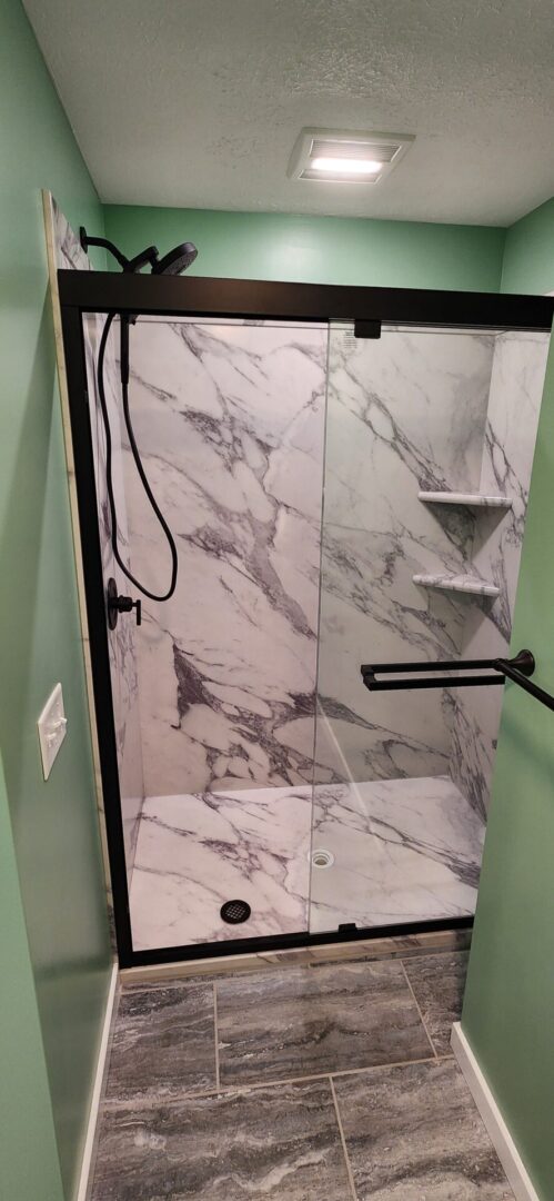 A bathroom with marble walls and black fixtures.