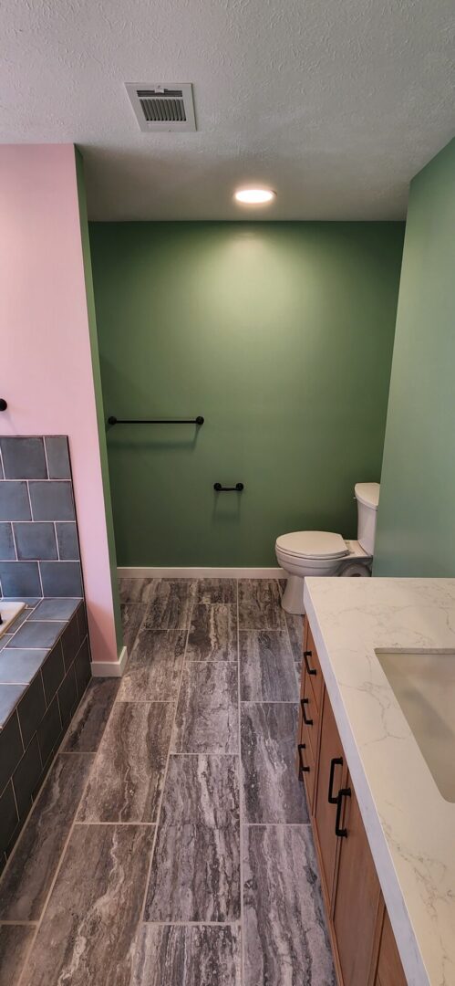 A bathroom with green walls and pink accents.