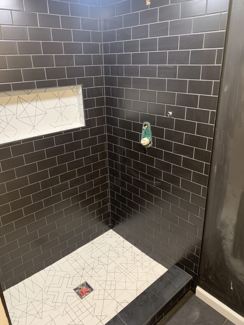 A bathroom with black tile and white floor.